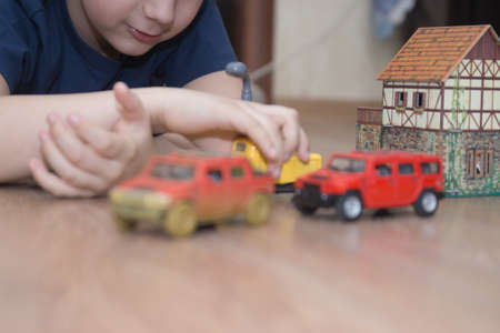 Boy is playing toy cars on the floor