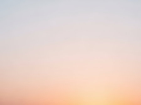 A serene and calming image of a sunrise sky with soft pastel colors blending together. The gradient transitions from light blue at the top to warm hues of pink and orange near the horizon, creating a peaceful and tranquil atmosphere.の素材