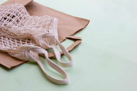 Paper and mesh textile bags for zero waste shopping on green background. Space for text.の写真素材