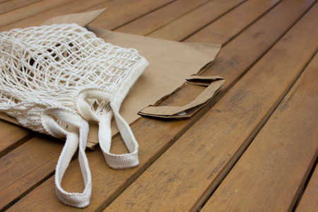 Paper and mesh textile bags for zero waste shopping on brown wooden background. Space for text.の写真素材