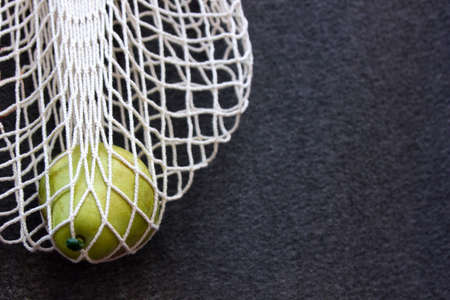 Ecological lifestyle concept with fresh pear in reusable shopping bag. Eco-friendly mesh bag with pear in it. Reduce plastic packaging concept. close up, nobody on the gray backgroundの写真素材