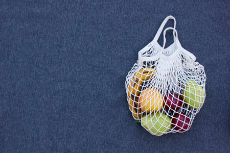 mesh eco zero waste shopping bag with fruits top view on the gray background, close up with space for textの写真素材