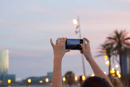 Barcelona, Spain, 02 May 2020. female hands holding her mobile phone and taking photo in with smartphone in Barceloneta beach, Barcelona, Spain on the first day of the end of lockdownのeditorial素材
