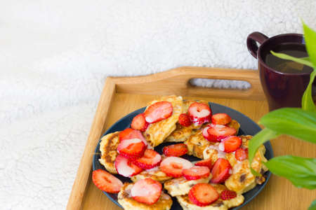 breakfast tray set up on a bed with healthy pancakes with strawberry, hot drink and green plant on the white background. Breakfast in bed morning concept. Space for text. Mockupの写真素材