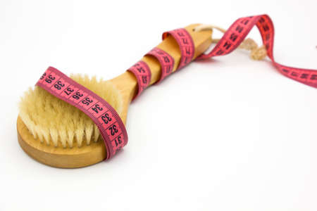 Dry massage brush with tape measure on white desk. Health and diet. Fitness concept.