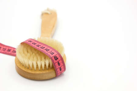 Dry massage brush with tape measure on white desk. Health and diet. Fitness concept.