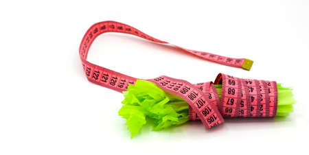 Pink measuring tape and celery isolated on white. Slimming, diet, and control of weight. Healthy nutrition. Healthy lifestyle concept. Control of weight during the isolation periodの写真素材