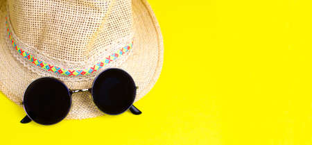 Straw beach woman's hat and black sun glasses, top view yellow paper background. Space for text. Banner. Summer is comming.の写真素材