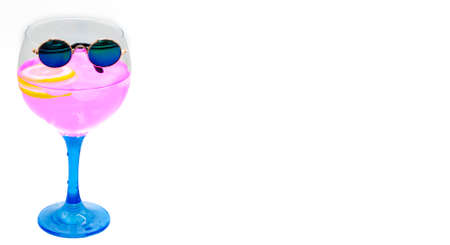 Glass of pink gin tonic with lemon and little sunglasses on white background. Space for text.の写真素材