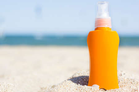 Orange Sunscreen Cream Bottle On The Beach. Summer time on the beach with sunblock. Sea and blue sky...