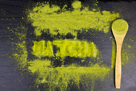 Word MATCHA Piled Of Green Powder On dark Background. Spoon with matcha green tea. Superfood. DIY...