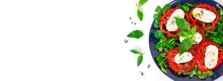 Italian caprese salad with ripe tomatoes and mozzarella cheese with fresh basil leaves and corn salad. Delicious food. White background with space for text. Banner. Healthy and tasty dinner. Top viewの写真素材