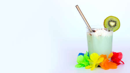 Tropical caribbean exotic green cocktail with slice of kiwi in a glass with metal cocktail tube and hawaiian flower garland isolated on white. Space for text. Milkshakes and smoothieの写真素材