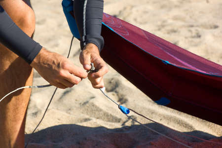 Kitesurfer on the beach preparing the equipment. male hands fixing kitesurf lines on a comet or kite before entering the sea. Kitesurfing equipment for kite courses. Extreme watersports. Wild lovers.の写真素材