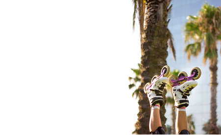 Girl's legs wearing socks and rollerskates upside down against a palm trees in the park. Space for...