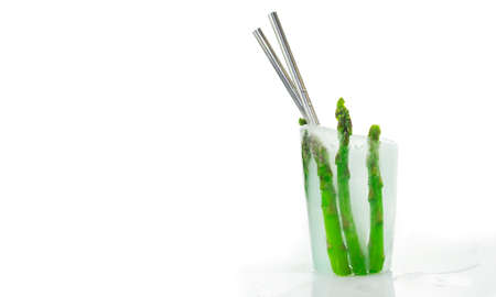 Refreshing and delicious healthy vegetable cocktail for hot summertime. Iced glass with green raw asparagus and metal reusable straws on white backgroundの写真素材