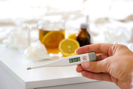 selective focus on a thermometer with a temperature of 37. A womans hand holding a thermometer...