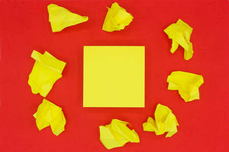 Stack of sticky notes in the middle and crumpled notes around. Yellow blank stickers on red background.の写真素材