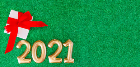 gift box and numbers 2021 on a green background. Happy New Year concept. White box with a present...