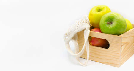 Assorted Fresh Apples on wooden box with eco-friendly reusable cloth mesh on white background with...