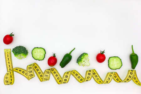 Healthy clean eating or diet plan concept. Different vegetables with yellow measuring tape on white...