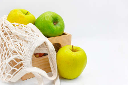 Assorted Fresh Apples on wooden box with eco-friendly reusable cloth mesh on white