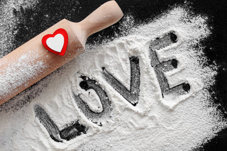 Preparation for baking home made cookie or pizza for Valentine's Day. Top view, flat lay. rolling pin, flour, red and white heart and text love. St Valentines Day ornament food background.の写真素材