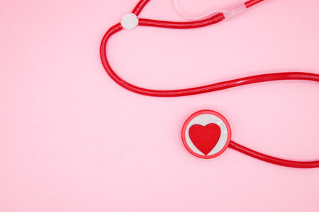 Red stethoscope with heart on pink background with space for text. Valentines Day, love concept.の写真素材
