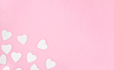 Wooden white hearts on soft pink color background, border, copy space. Valentine day concept for design.の写真素材