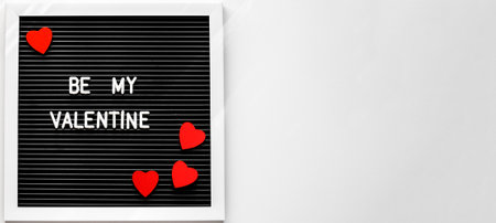 Modern black board with text 'Be my Valentine' and red wooden hearts on a white background. Valentine's Day 14 February. Space for text.の写真素材