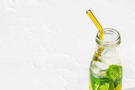 Bottle with lemonade and glass straw on white background. Drink with fresh lemons. Water with lemon,...