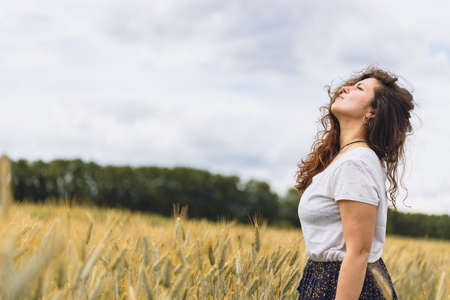 Young carefree woman in rustic dress Breathing Deep Fresh Air In A grassy Field. Space for text. walking in summer meadow. Atmospheric authentic moment. Rural slow lifeの写真素材