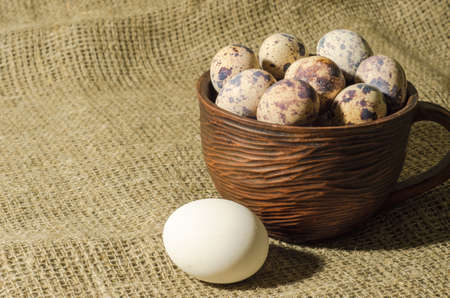 chiken egg, eggs of quail in the clay cup, sacking backgroundの写真素材