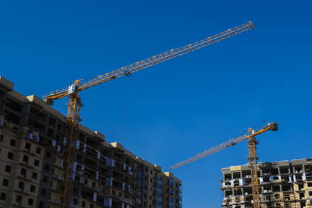New buildings and constraction craines on blue sky background.