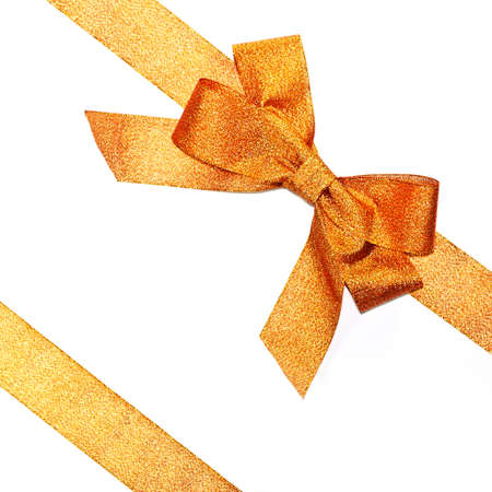 Golden sparkling holiday bow with ribbon on white backgroundの写真素材
