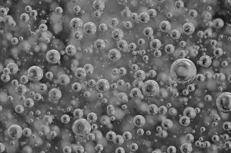 Black-and-white background with big and small grey bubbles inside a gray liquid.の写真素材