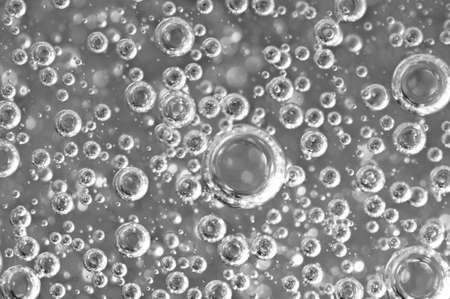 Black-and-white background with big and small grey bubbles inside a gray liquid.の写真素材