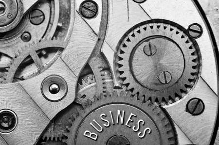 Background with the inscription BUSINESS. Black white background with metal cogwheels clockwork. Macro. Conceptual photo for your successful business design. Metallic black and white letters, gears. Concept teamworkの写真素材