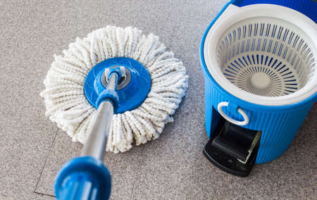 mop and blue bucket  cleaning a  floor from dust