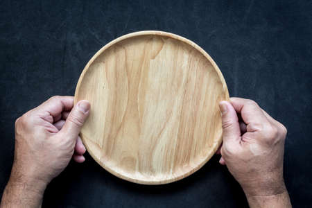 Man hands hold a empty wooden plateの写真素材