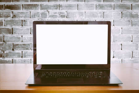 Open laptop on an office desk in front of brick wall backgroundの写真素材