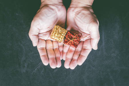 Gift box in hand on black backgroundの写真素材