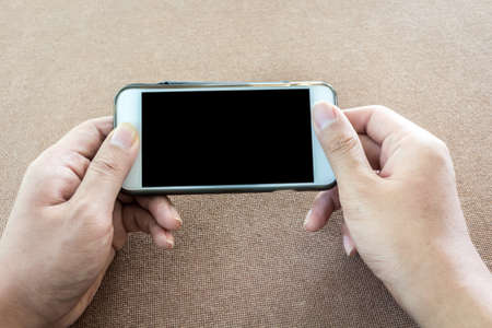 Hands holding smart mobile phone on wooden table backgroundの写真素材