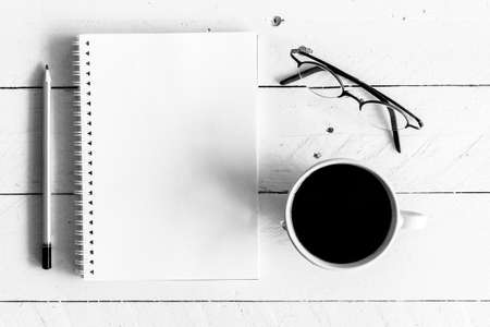 Black coffee with notebook and pencil on wooden background - black and whiteの写真素材