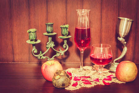 Still life image of red wine and fruits over wooden background