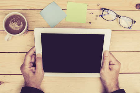 Businessman with tablet pc computer and coffee cup on wooden tableの写真素材