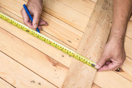 Male hands measuring wood flooringの写真素材