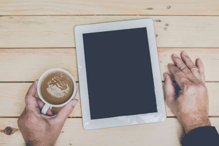 Businessman with tablet pc computer and coffee cup on wooden table