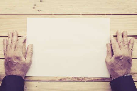 Businessman hold the pages of a book on the wooden deskの写真素材
