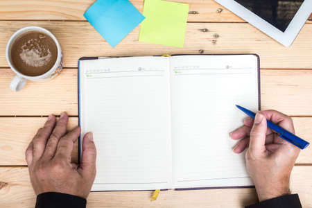 Businessman with  coffee cup and notebook on wooden table